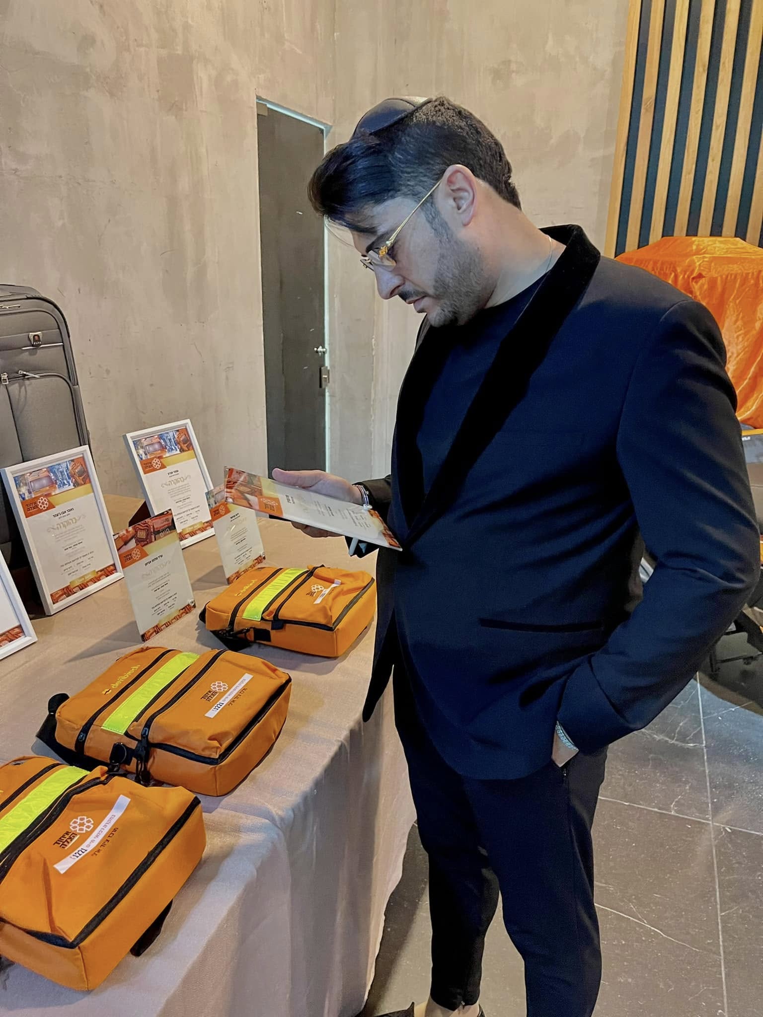 אדם שטרית לצד תיקי ציוד של איחוד הצלה ותעודות הוקרה באירוע למתנדבים