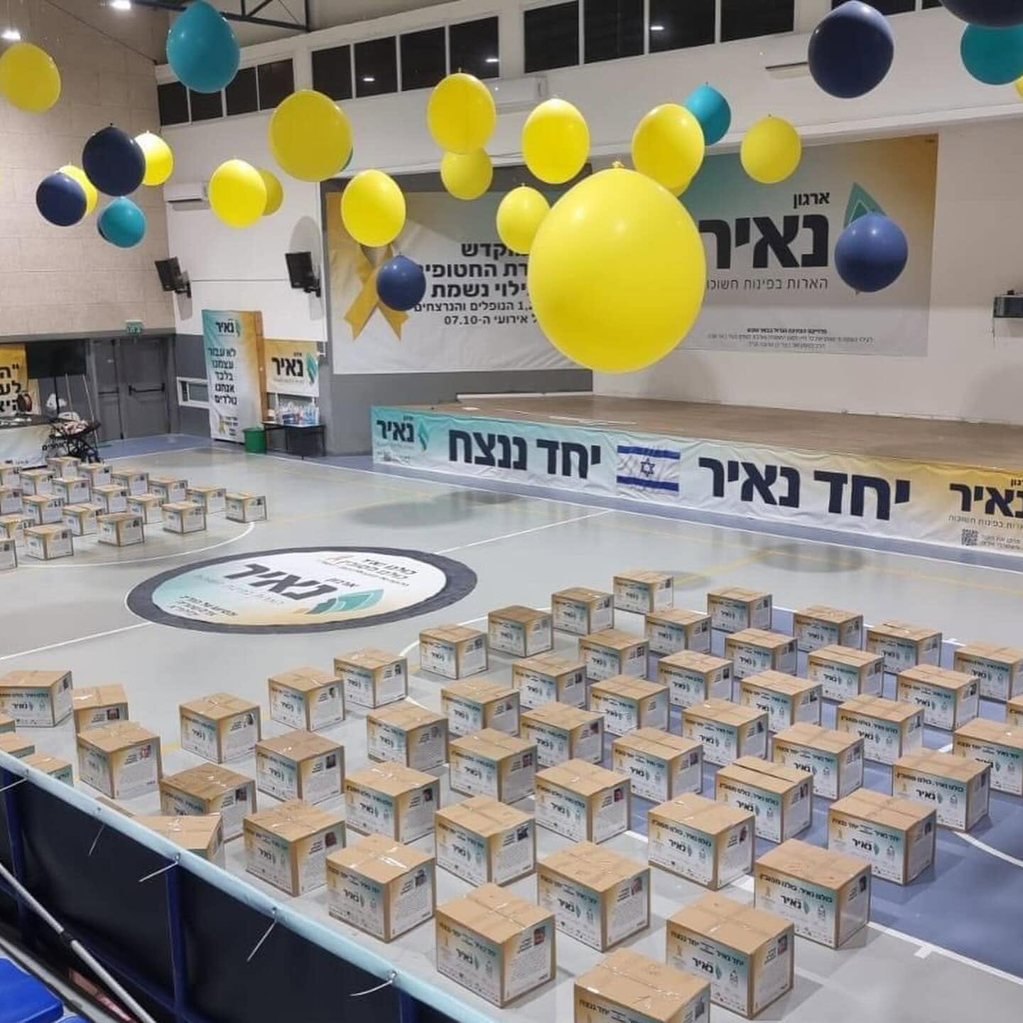 סלי מזון מסודרים באולם הפעילות של ארגון נאיר מתחת לבלונים צבעוניים