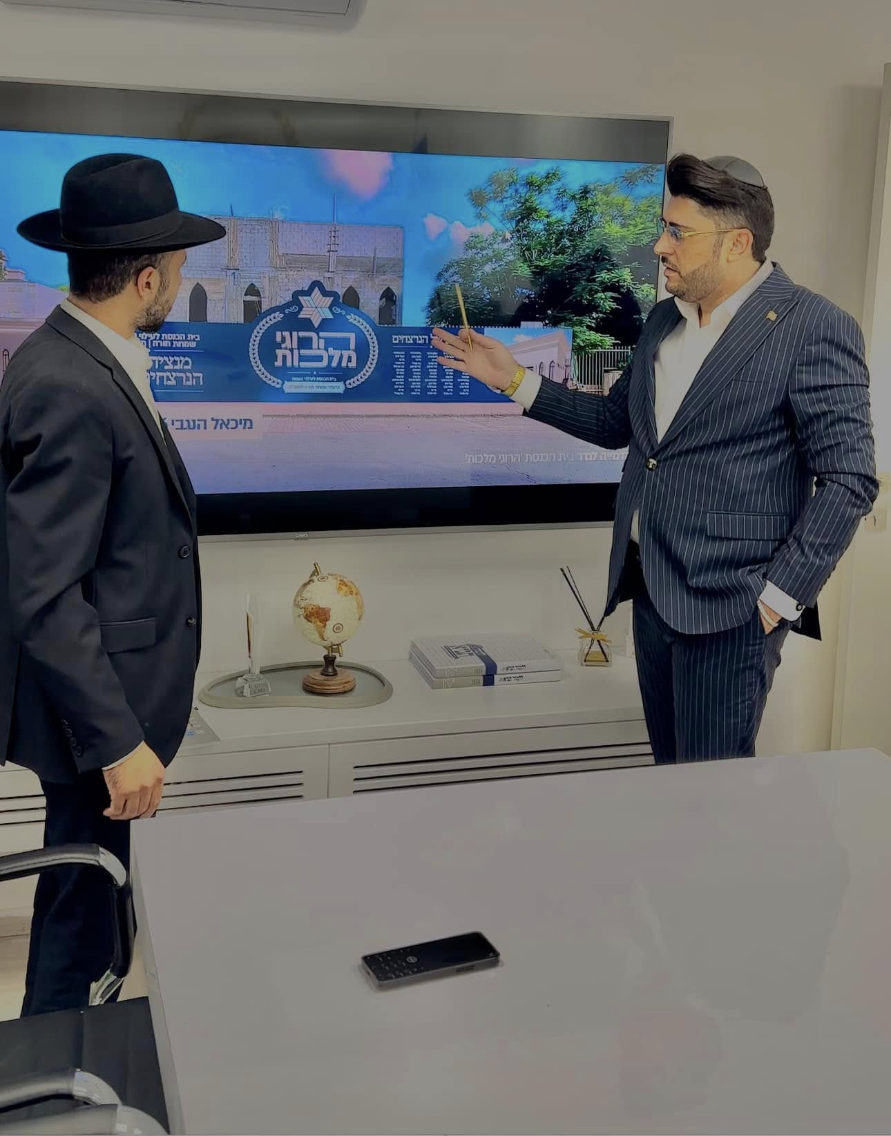 אדם שטרית מציג את חזון בית הכנסת "הרוגי מלכות" על מסך במשרד